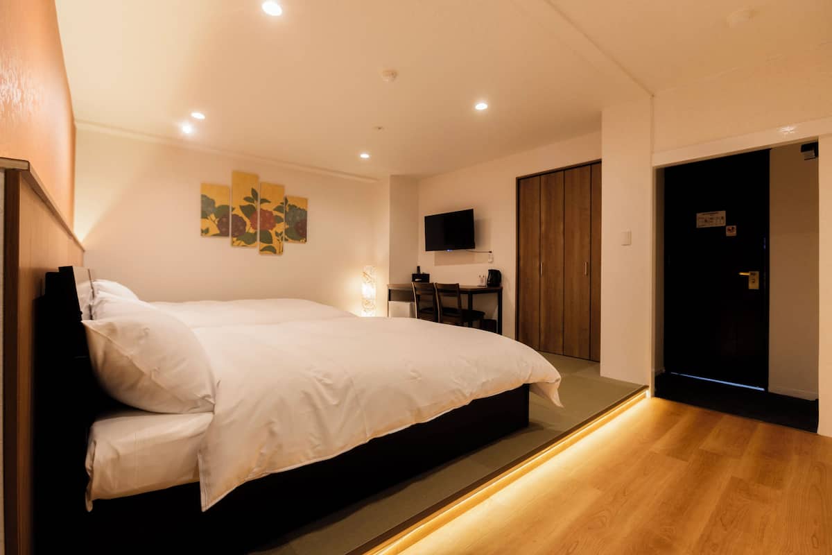 Un dormitorio moderno con una cama grande, un escritorio, una silla y un televisor fijado a la pared.