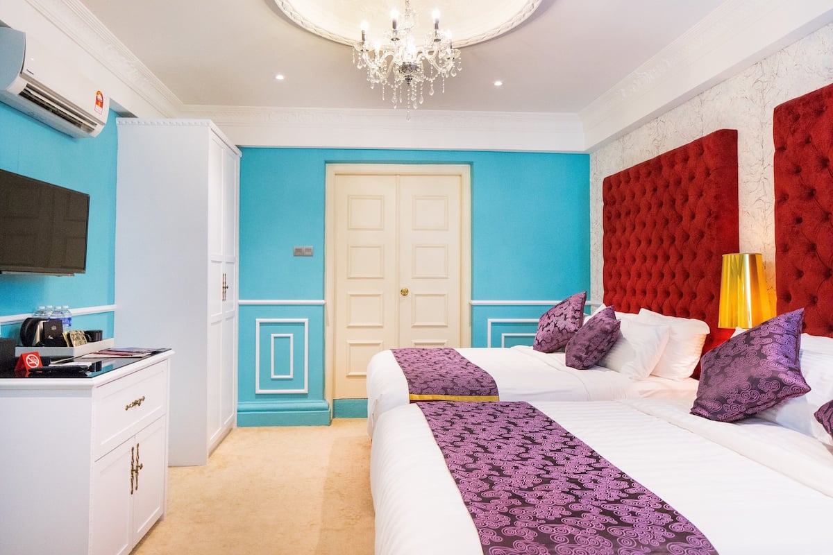 Camera da letto con un grande letto, una testiera imbottita rossa, un lampadario e un'armadio bianco.