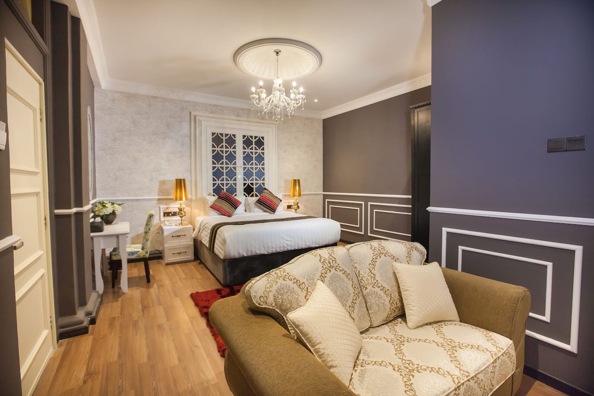 Una camera da letto con un letto, comodini, un lampadario e un divano.