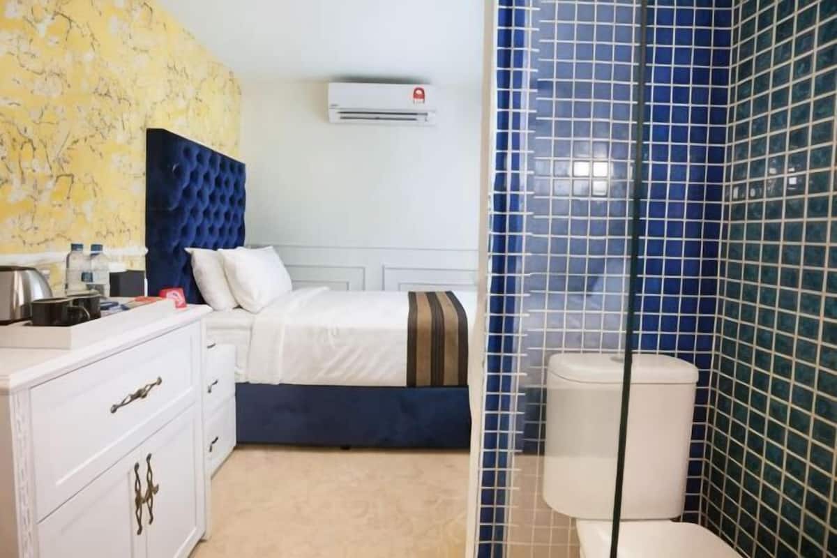 Una camera d'albergo con un letto, una cassettiera, un mobiletto da trucco e un water.