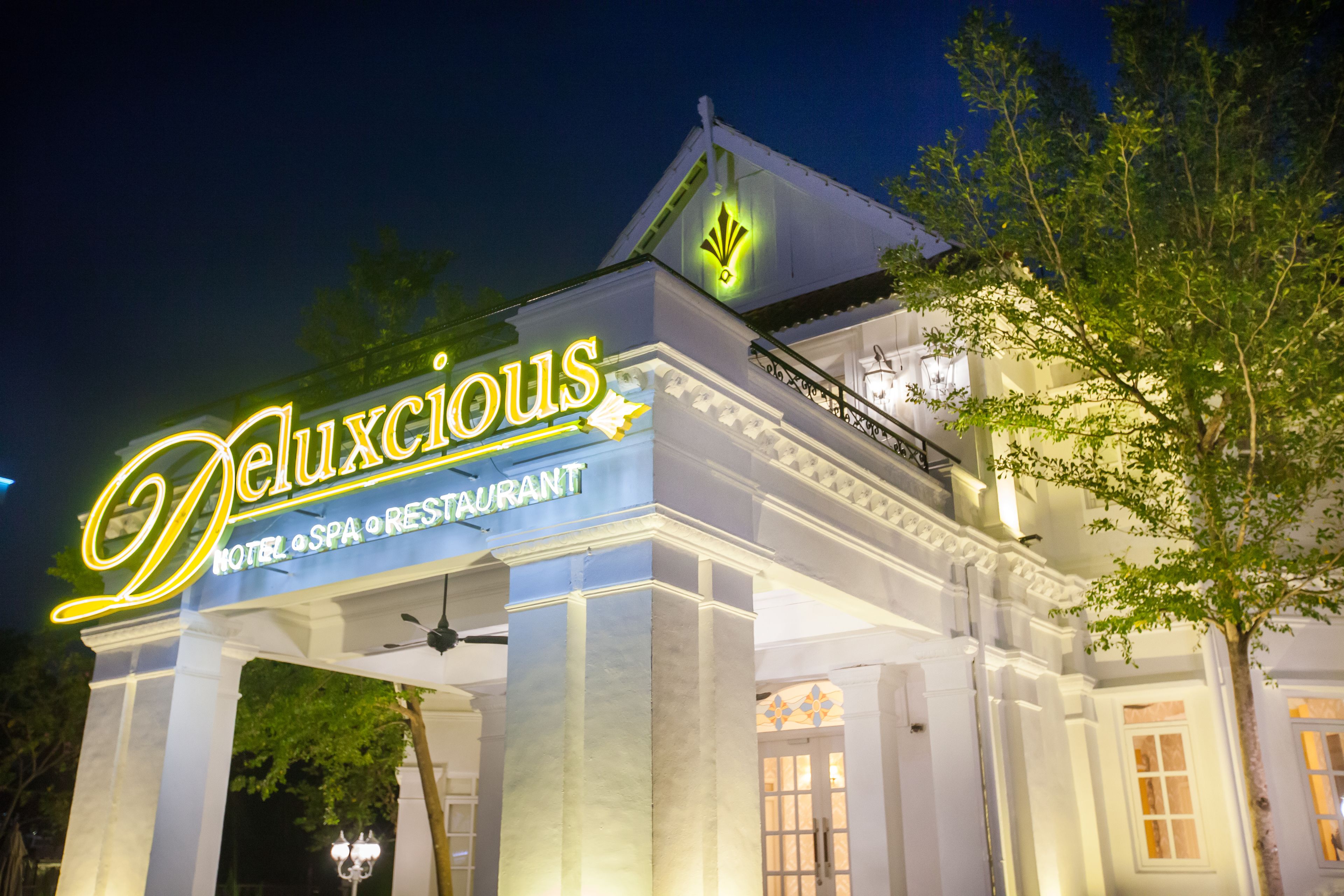 A hotel named 'Deluxious' with a sign indicating it is a hotel, spa, and restaurant.