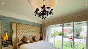 Un dormitorio amplio con una cama grande, una araña de cristal y vistas al exterior.