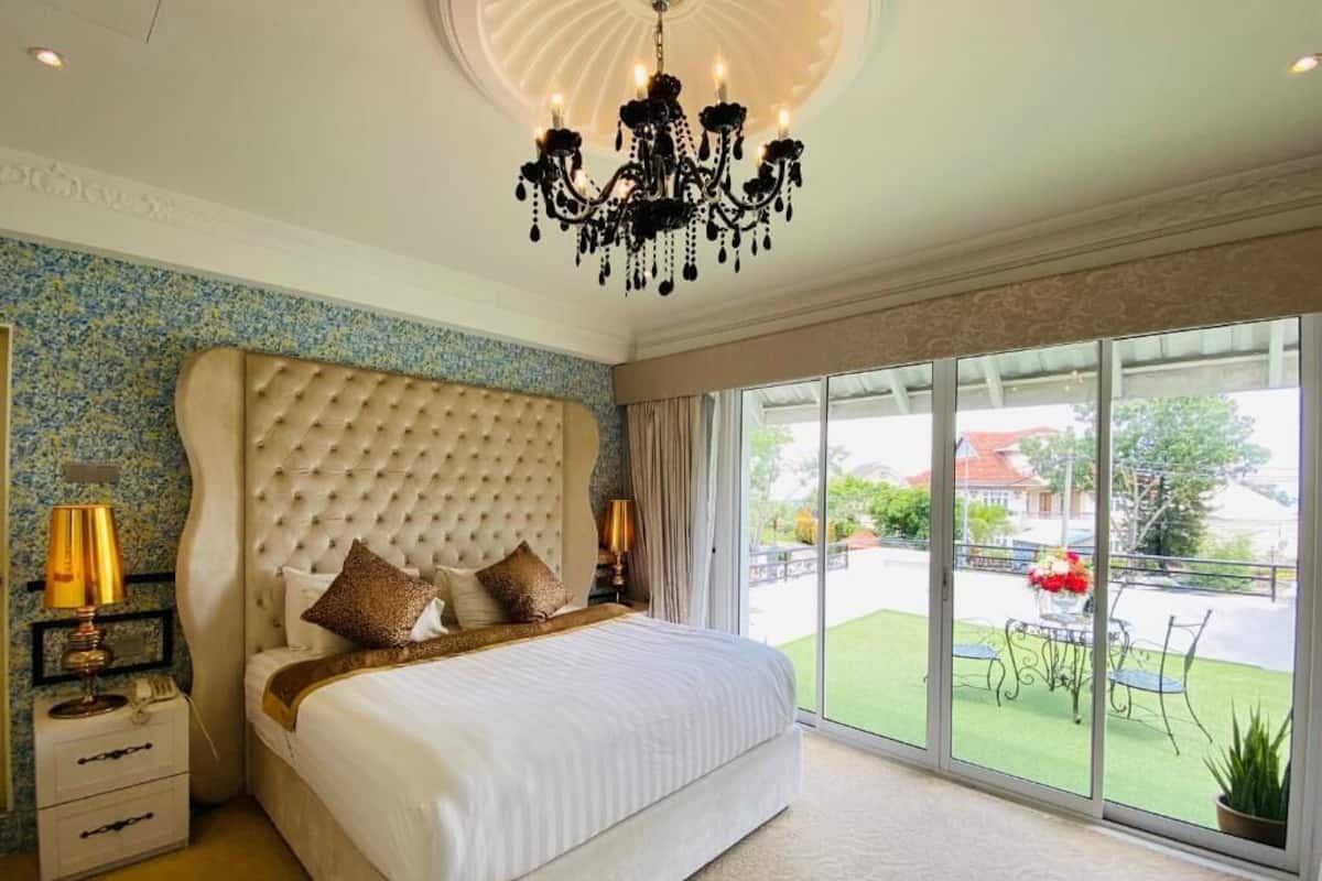 Un'ampia camera da letto con un grande letto, un lampadario e vista sull'esterno.