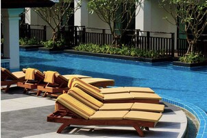 A pool area with lounge chairs and a tiled deck.