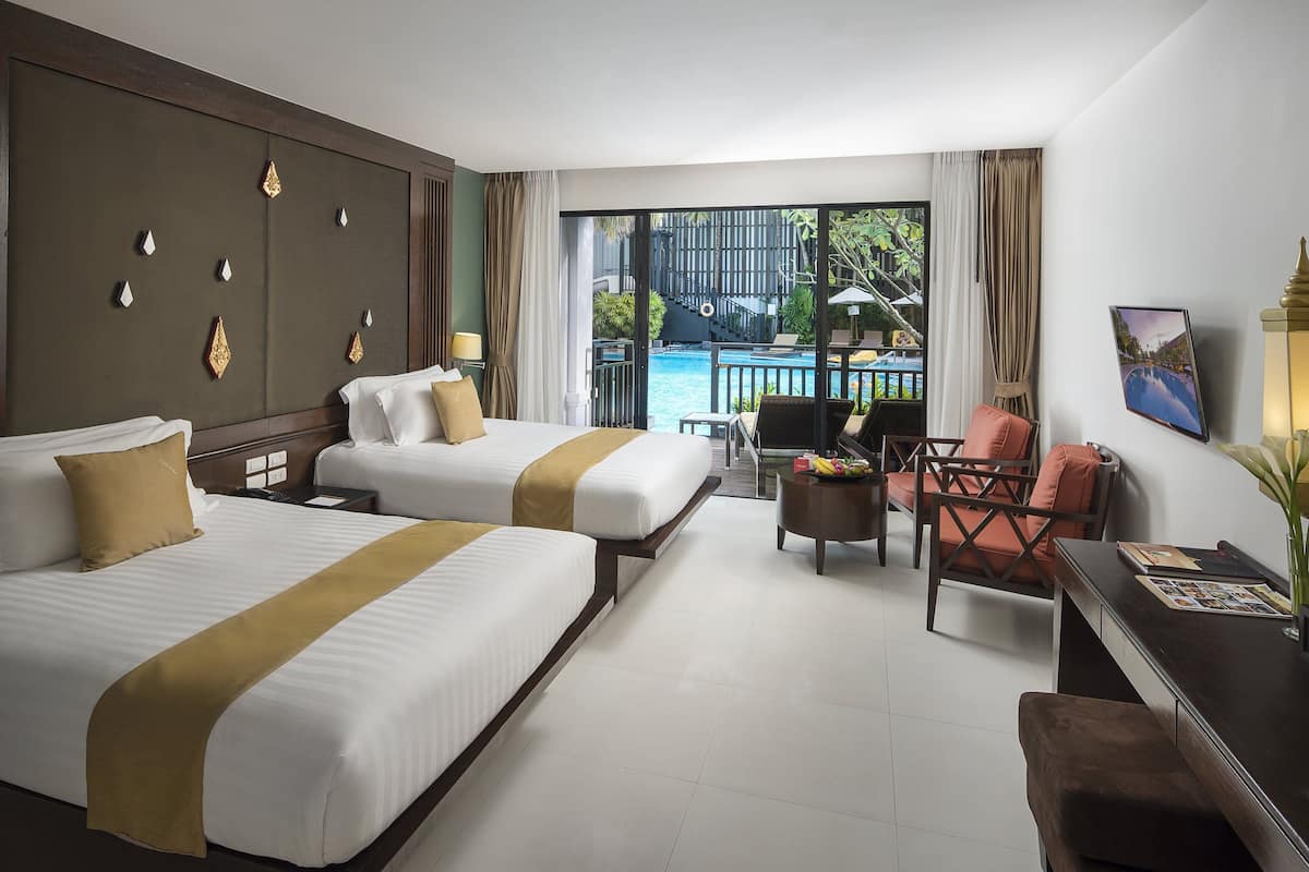 Une chambre d’hôtel avec deux lits, un coin salon avec une table et des chaises, et une vue sur une piscine.