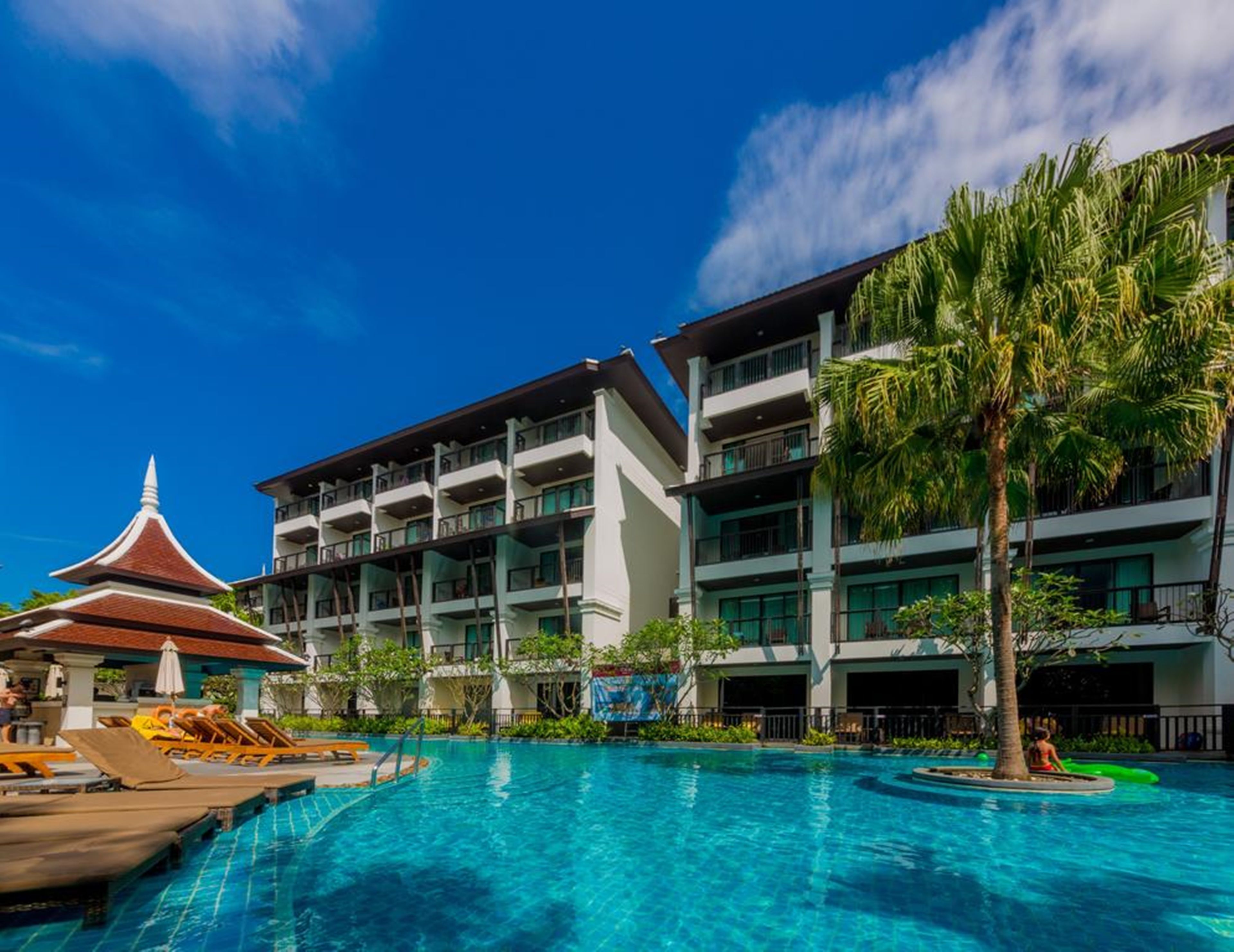 Ein Hotel mit Schwimmbad, mehreren Balkonen und einem traditionellen Gebäude mit spitzem Dach.