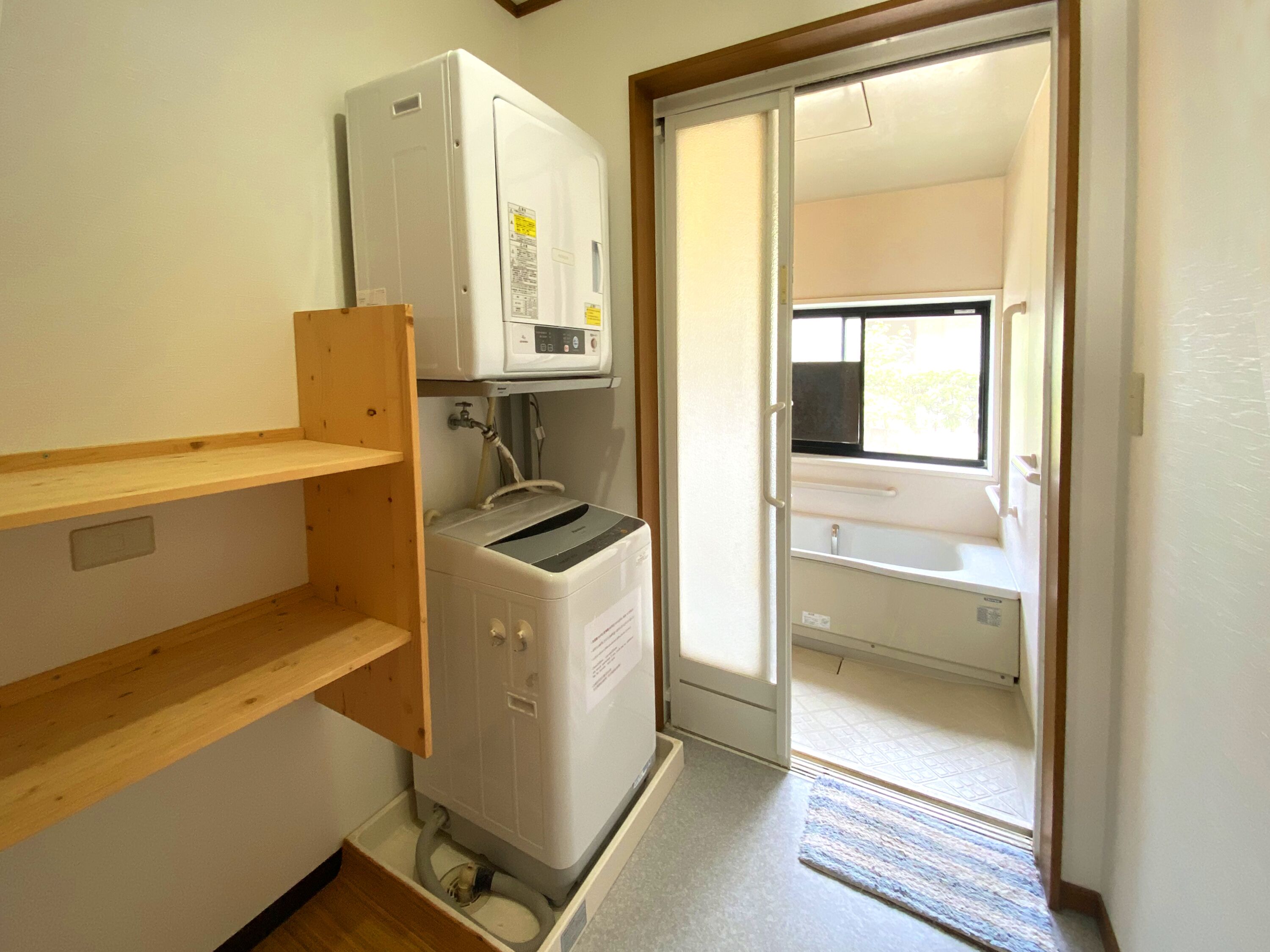 A compact laundry room with a washing machine, a dryer, and a small window.