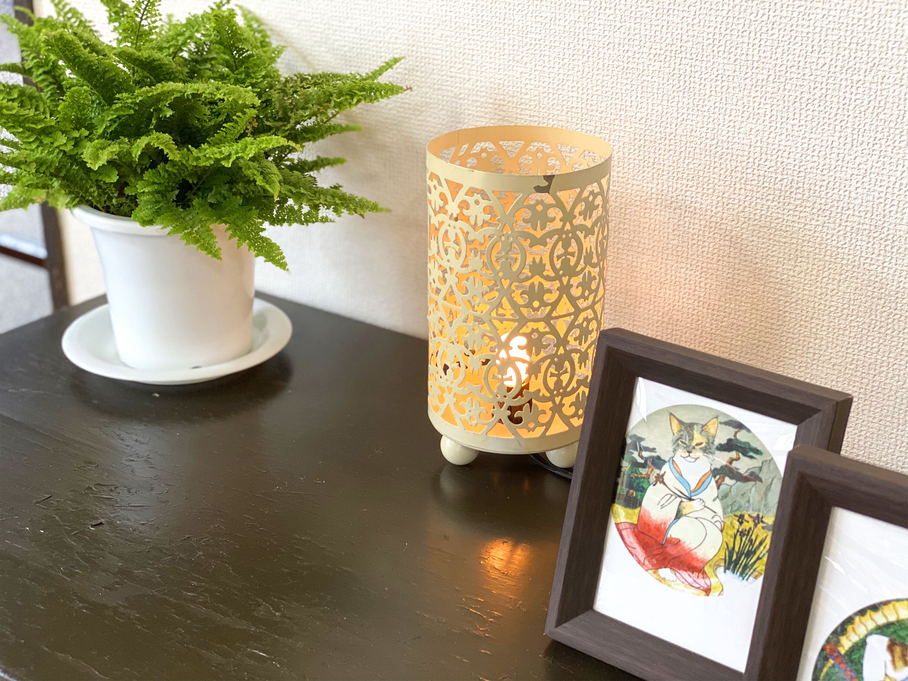 A potted plant, a decorative lantern, and framed artwork on a table.