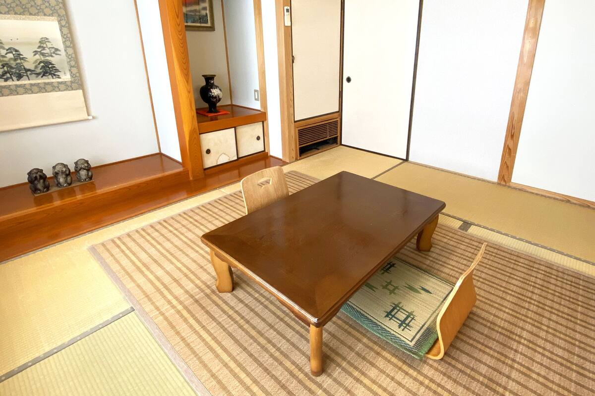 A traditional Japanese room with tatami flooring, a low wooden table, and sliding doors.