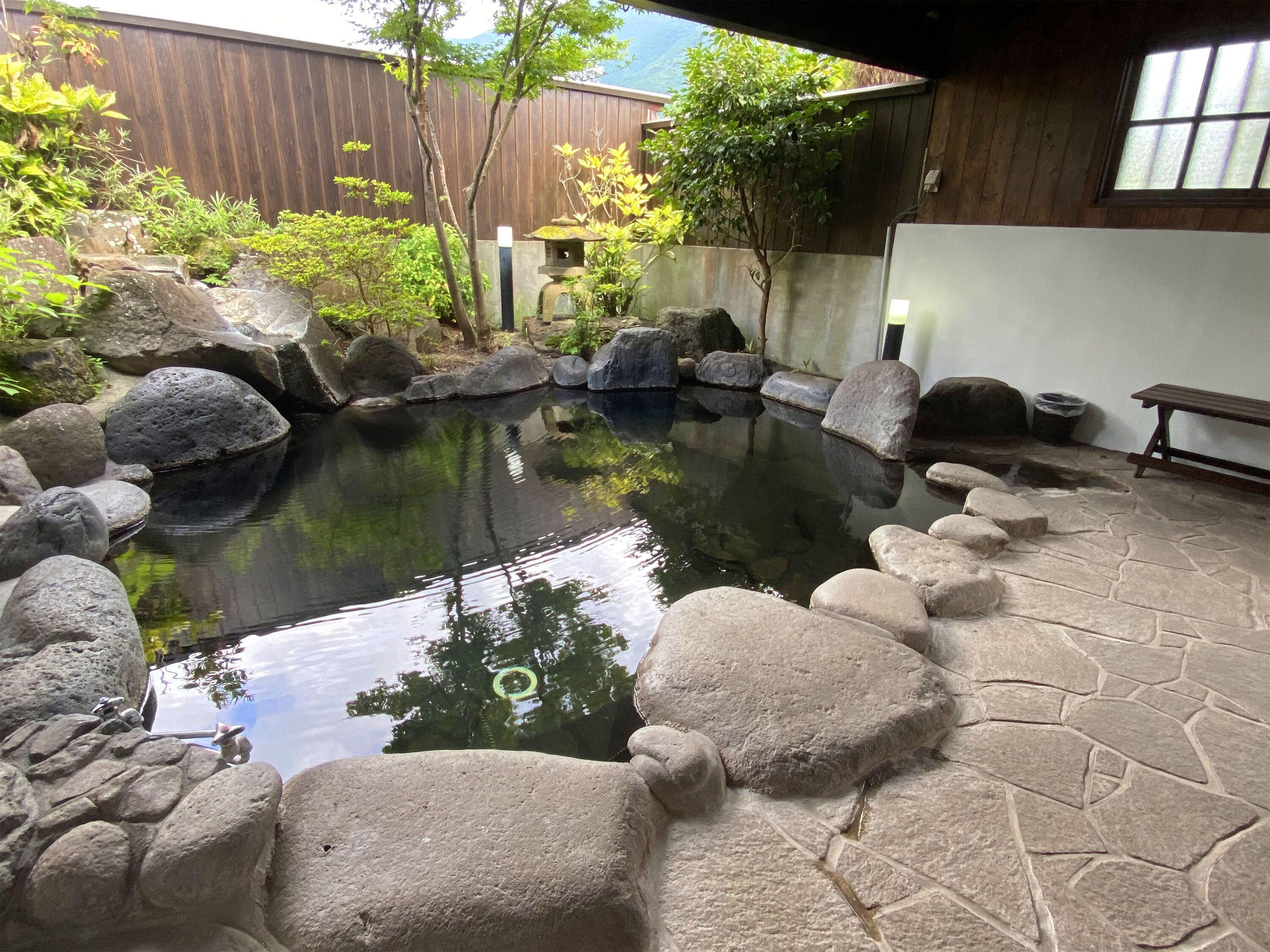A koi pond surrounded by large rocks and a wooden deck.