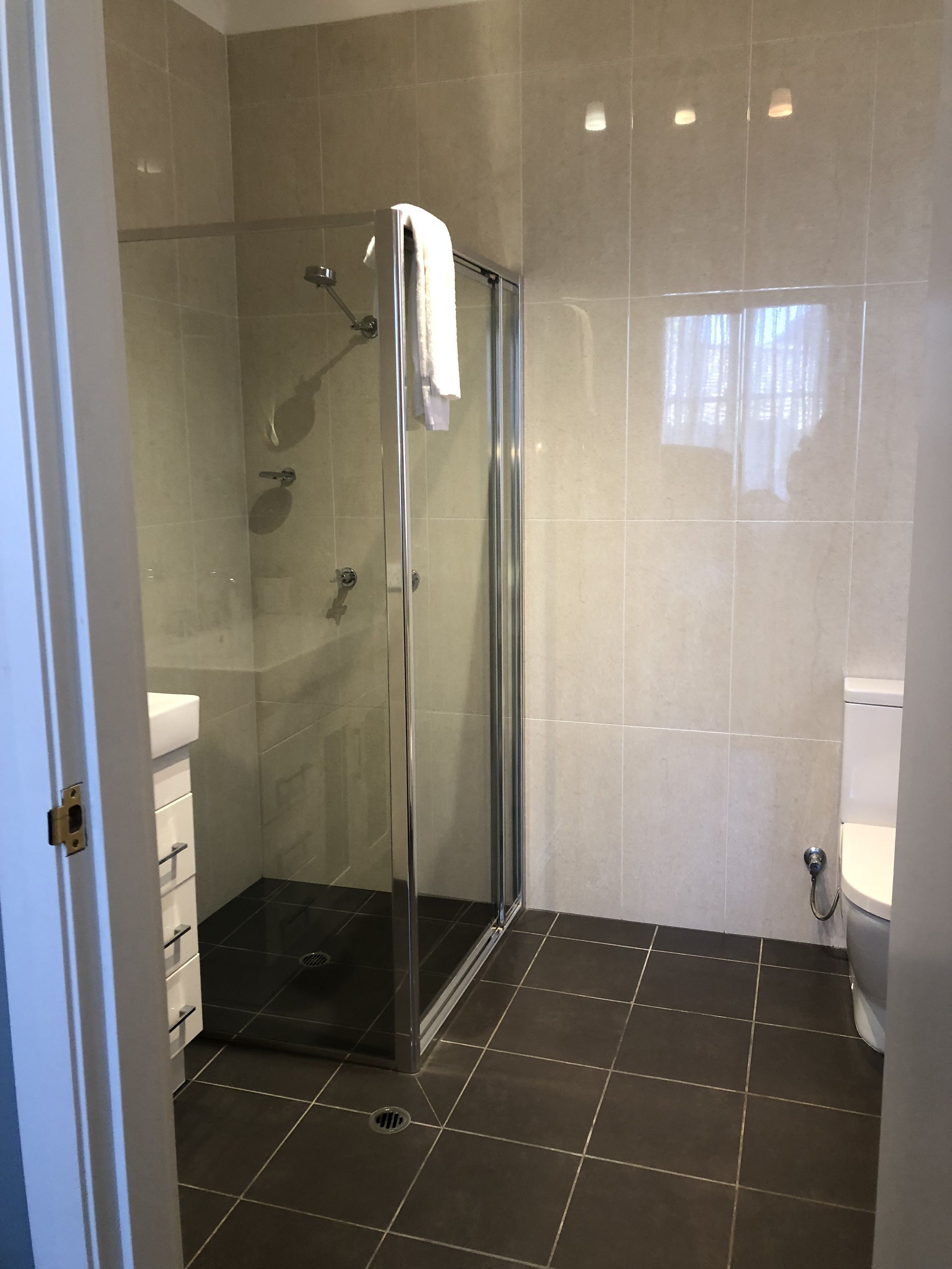 A modern bathroom with a glass-enclosed shower, a white toilet, and a sink with a white countertop.