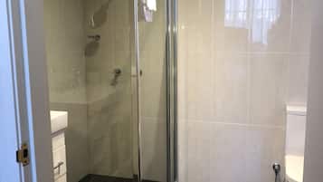A modern bathroom with a glass-enclosed shower, a white toilet, and a sink with a white countertop.