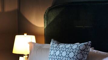 A neatly made bed with a patterned pillow, a bedside lamp, and a dark headboard.