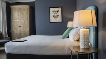 Een net opgemaakt bed met kussens, een bedlampje en een lijst met een vlinder afbeelding aan de muur.