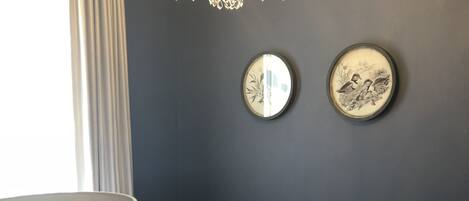 Un dormitorio con una cama, una araña y dos espejos adosados a la pared.
