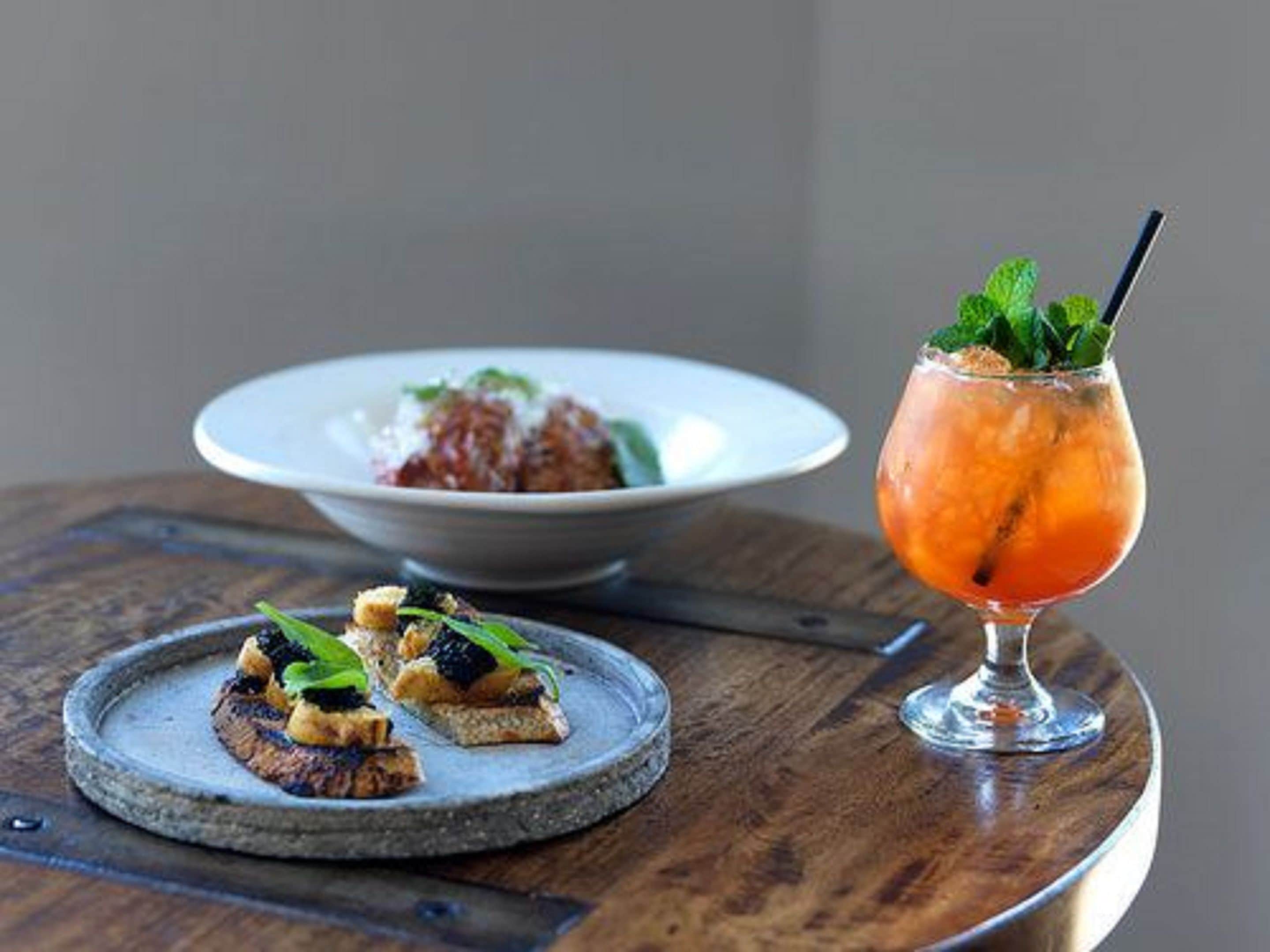 A wooden table with a plate of food and a cocktail glass.