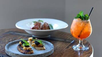 A wooden table with a plate of food and a cocktail glass.
