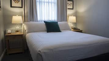 A neatly made bed with a green pillow, two bedside lamps, and framed butterfly pictures on the walls.