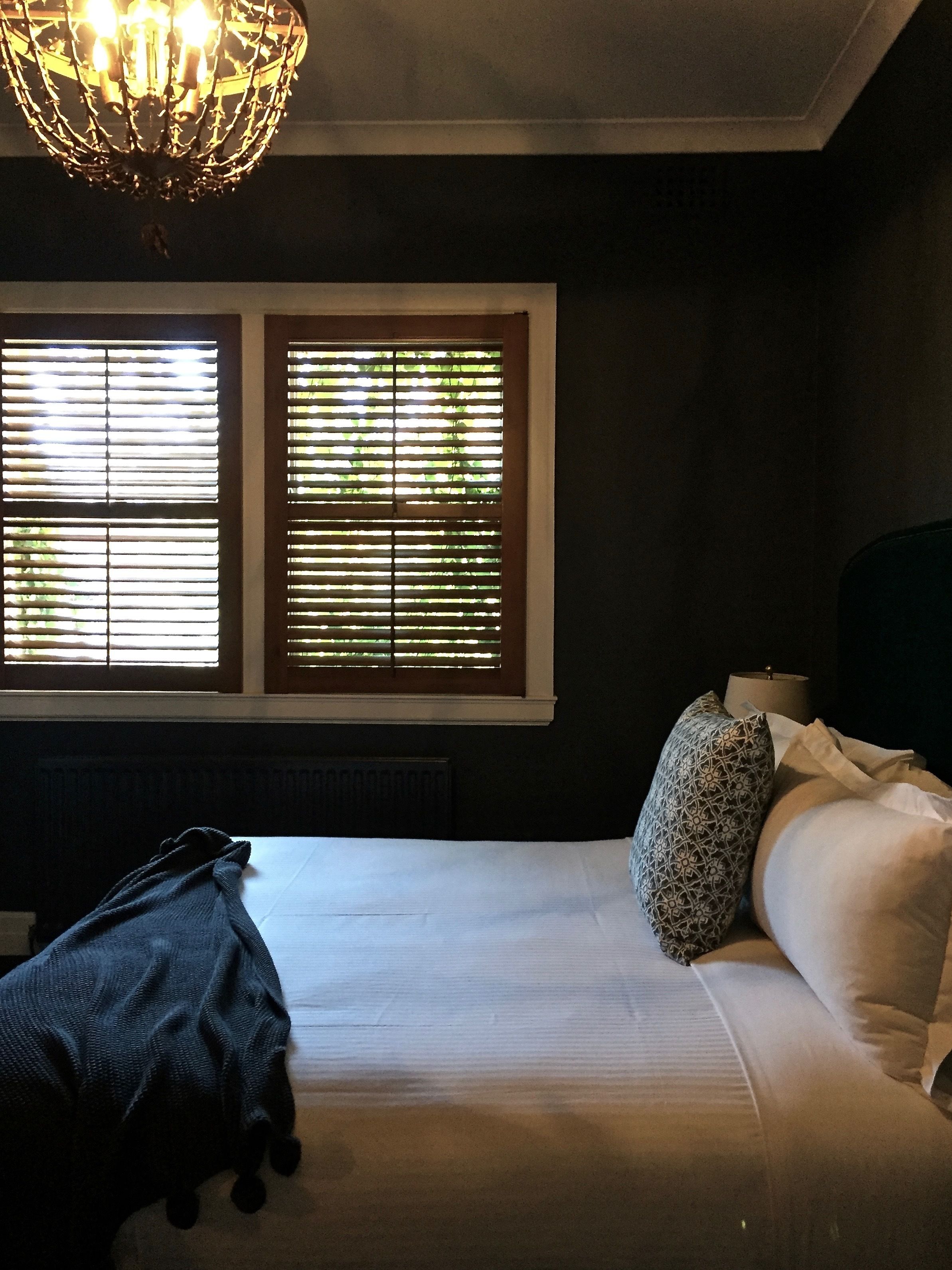 A bedroom with a bed, pillows, a blanket, and a chandelier.
