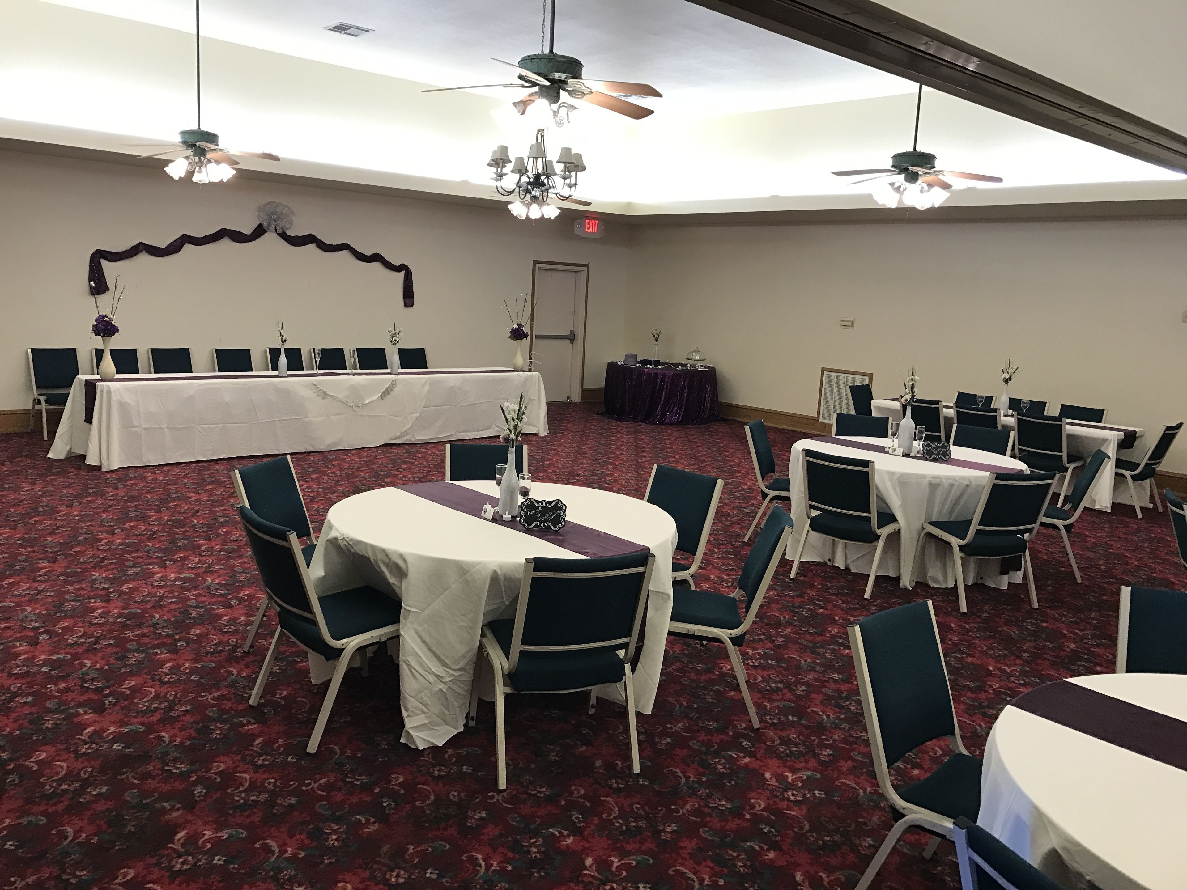 A conference room with round tables, chairs, and ceiling fans.