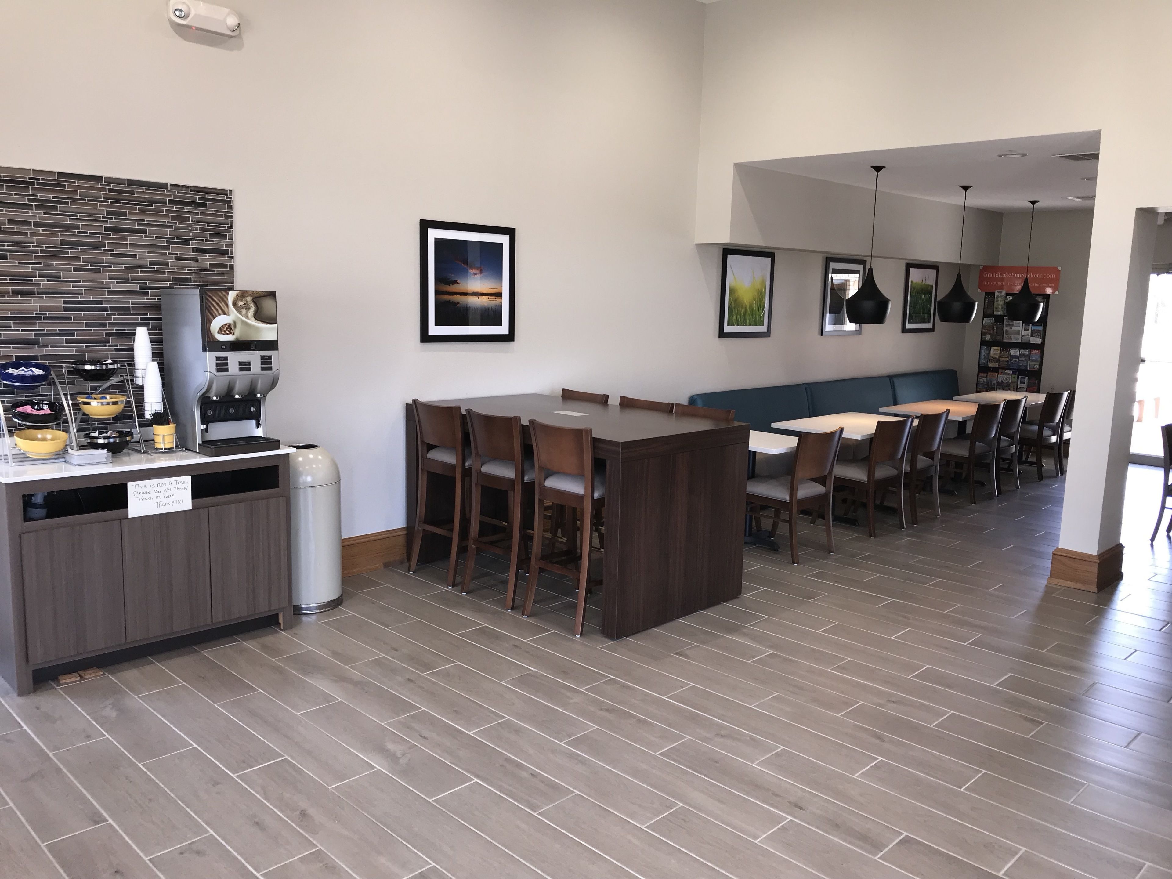 A modern dining area with a kitchen counter, seating arrangements, and a wall-mounted coffee machine.