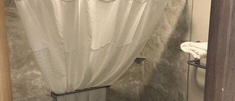 A bathroom with a shower curtain, a towel rack, and a toilet.