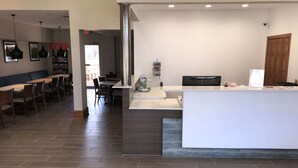 A modern reception area with a counter, seating, and a bulletin board.