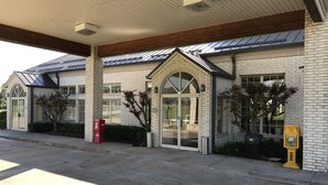 A building with a brick facade, large windows, and a covered entrance area.