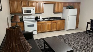 A compact kitchen with wooden cabinets, a microwave, a stove, and a refrigerator.