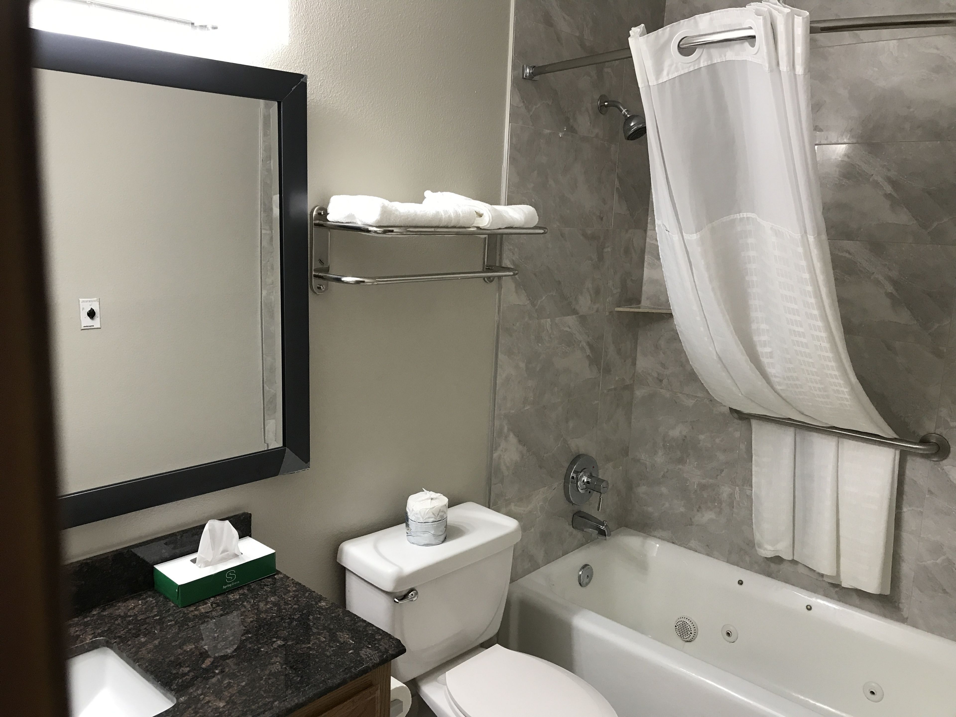 Une salle de bain comprenant des toilettes, un lavabo, un miroir, une douche et une baignoire.
