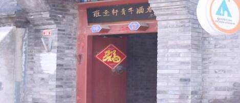 A traditional Chinese building with a red door, a sign above the door, and a logo on the right side.