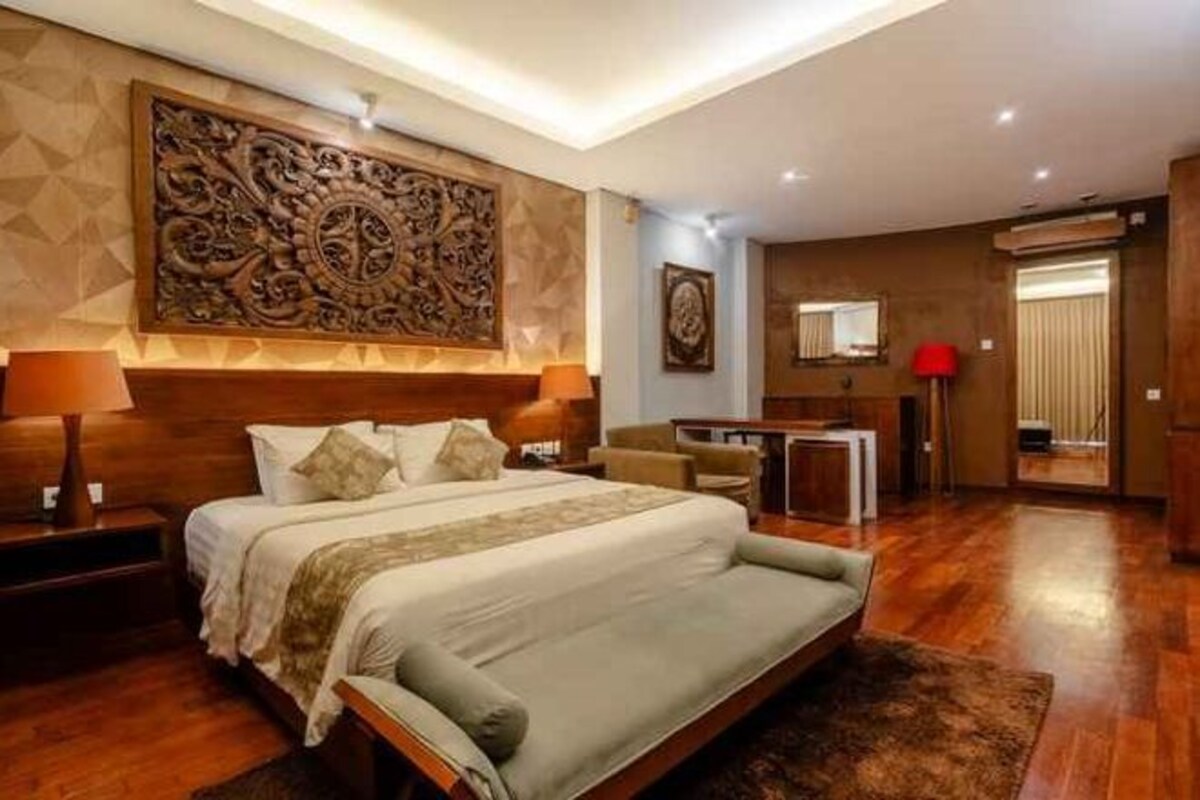 A bedroom with a large bed, bedside tables, a desk, and a chair.