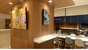 Un hall d’hôtel moderne avec des panneaux de bois, un comptoir d’accueil et deux œuvres d’art murales.