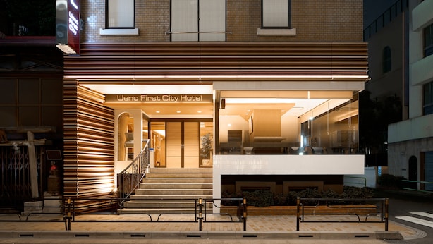 L’entrée d’un hôtel au design moderne, un escalier menant au hall d’accueil et une façade en verre.