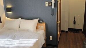 Une chambre d’hôtel équipée d’un lit, d’un téléphone sur la table de chevet, d’un porte-manteau et d’un porte-chaussures.