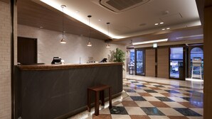 Un espace d’accueil doté d’un comptoir en marbre, de luminaires suspendus et d’un comptoir d’enregistrement.