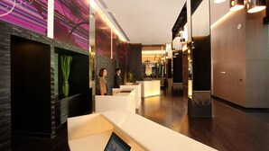 A modern hotel lobby with a reception desk, seating area, and a decorative wall with abstract patterns. - In Residence Bangkok Sukhumvit (Bangkok)