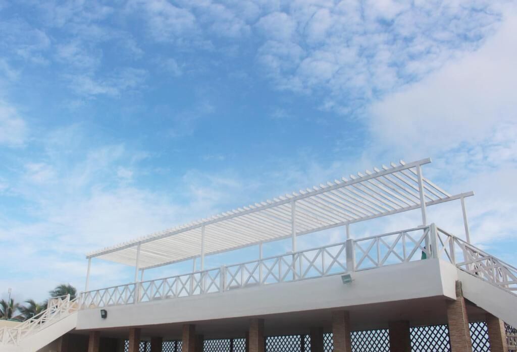 A building with a covered outdoor area and a staircase leading to a balcony.