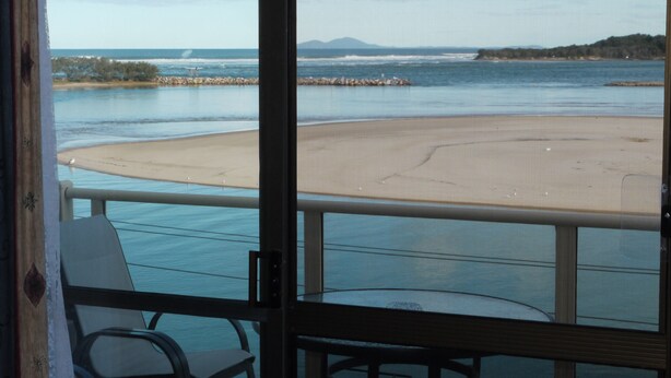 A view from a balcony overlooking a beach with a sandy shore and calm waters. - Marcel Towers Holiday Apartments (Nambucca Heads)