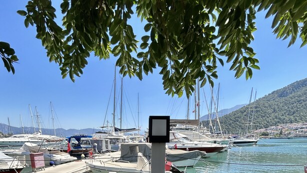 A table set for a meal with various dishes, a pizza, and a view of a marina with boats. - Marina Boutique Fethiye - Boutique Class (Fethiye)