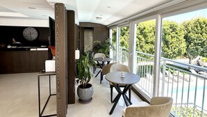 A spacious balcony with a pool view, a round table with chairs, and a potted plant. - Marina Boutique Fethiye - Boutique Class (Fethiye)