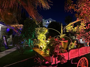 A nighttime garden with illuminated plants and a vintage cart. - Marina Boutique Fethiye - Boutique Class (Fethiye)