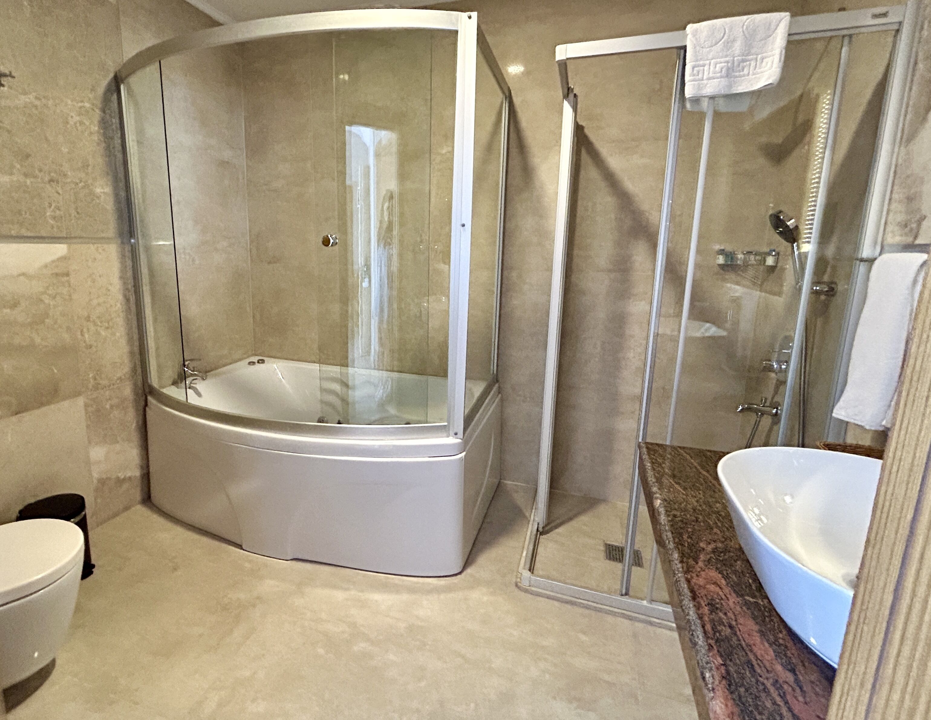 Un bany modern amb dutxa de vidre, una banyera independent i un taulell de marbre amb un lavabo.