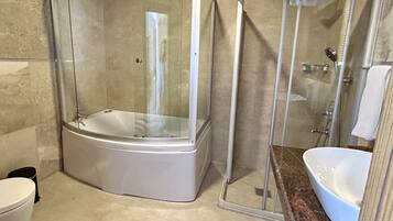 Un bany modern amb dutxa de vidre, una banyera independent i un taulell de marbre amb un lavabo.
