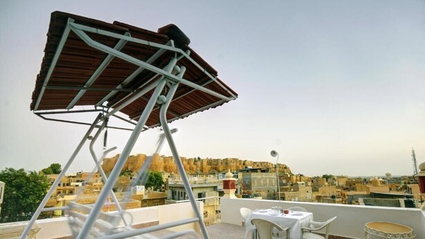 Eine Dachterrasse mit einem Metallstuhl, einem Tisch und einem kleinen runden Beistelltisch.