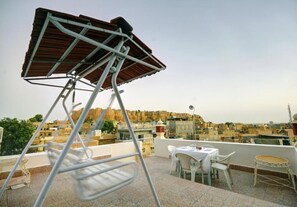 A rooftop terrace with a metal chair, a table, and a small round table. - Hotel Jaisal Palace (Jaisalmer)