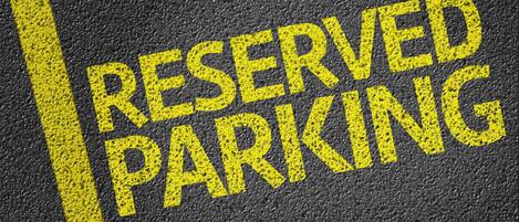 Primer plano de un letrero que dice 'RESERVED PARKING' pintado sobre una superficie texturizada.