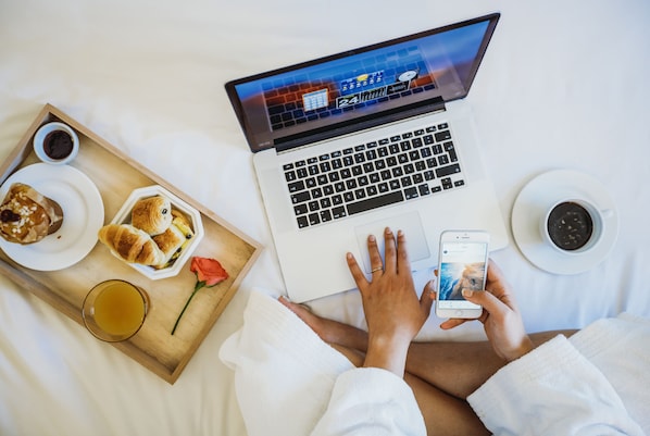 A laptop on a bed with a tray of food and drinks. - Ibis budget Charleroi Airport (Fleurus)