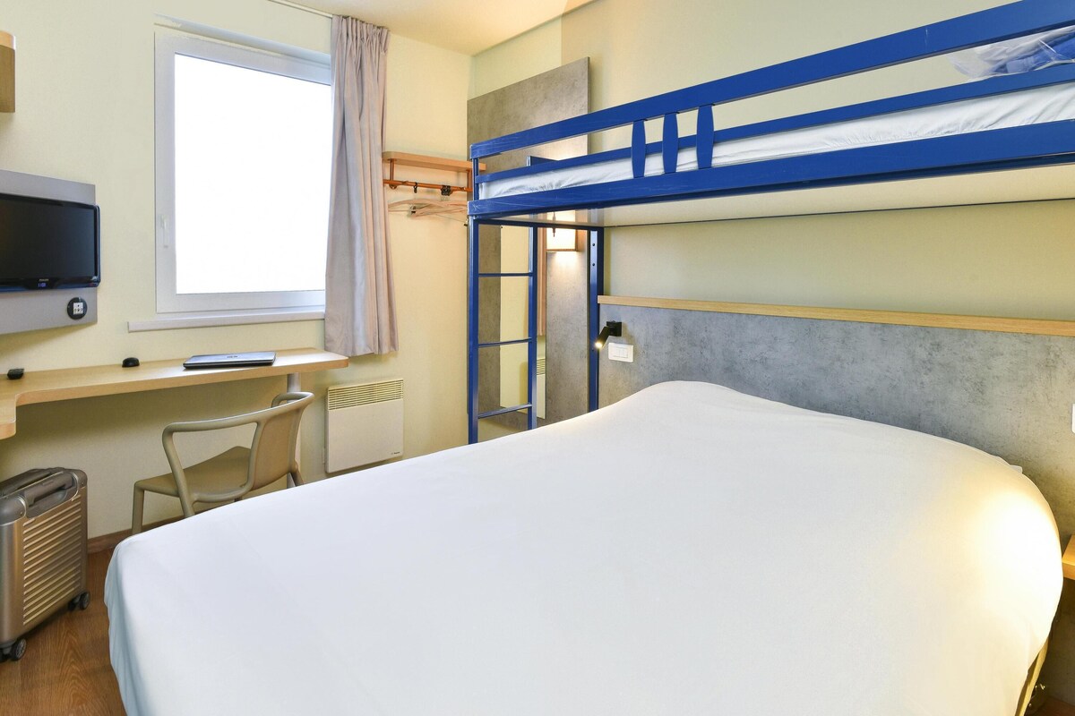 A bunk bed room with a desk, chair, and a television.