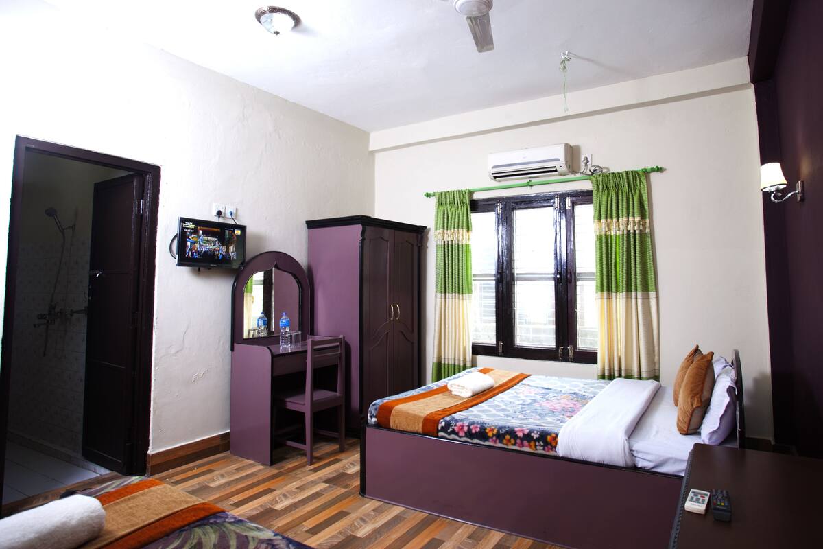 Une chambre à coucher comprenant un lit, un bureau, une armoire et un appareil de climatisation.